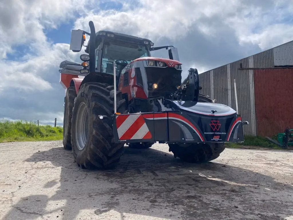 Large tractor fitted with a Massey Ferguson branded front weight bumper on a farmyard surface