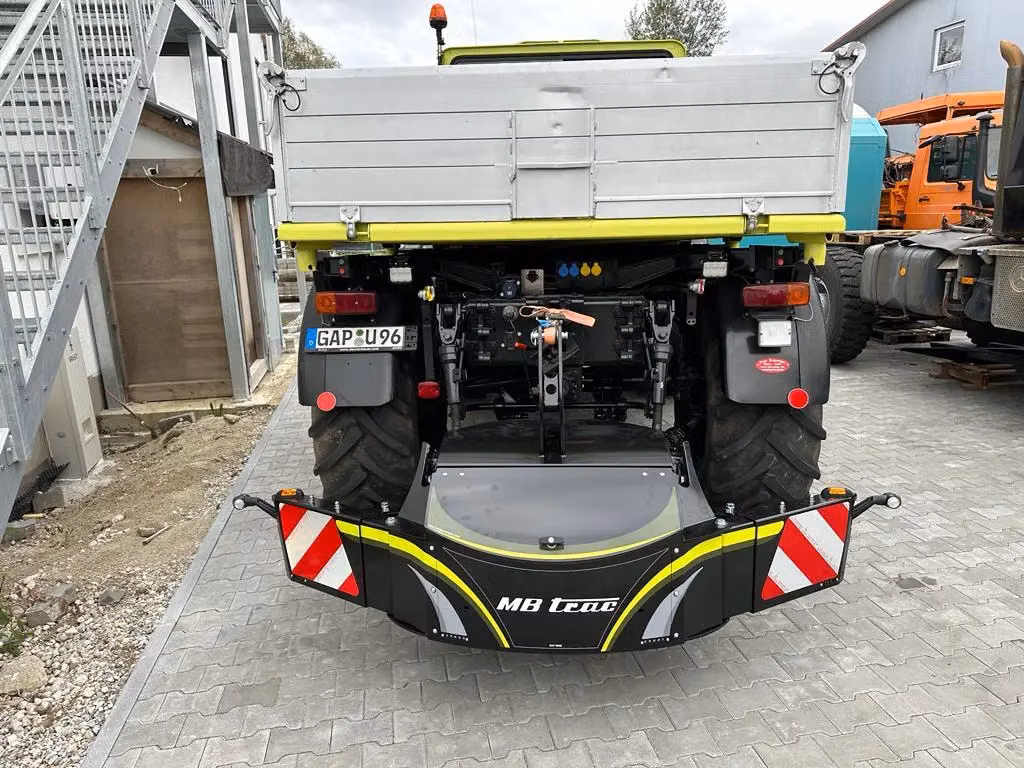 Rear view of a tractor with an attached MB trac front weight bumper featuring reflective red and white stripes