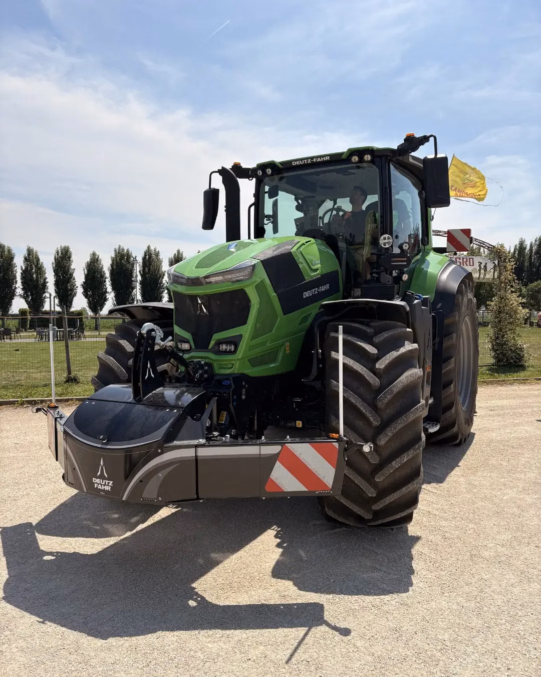 A green tractor fitted with a large front weight bumper featuring Deutz-Fahr branding and reflective stripes