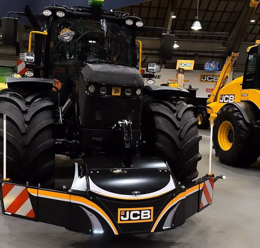 A large tractor with a JCB branded front weight bumper featuring LED lights and reflective warning stripes indoors