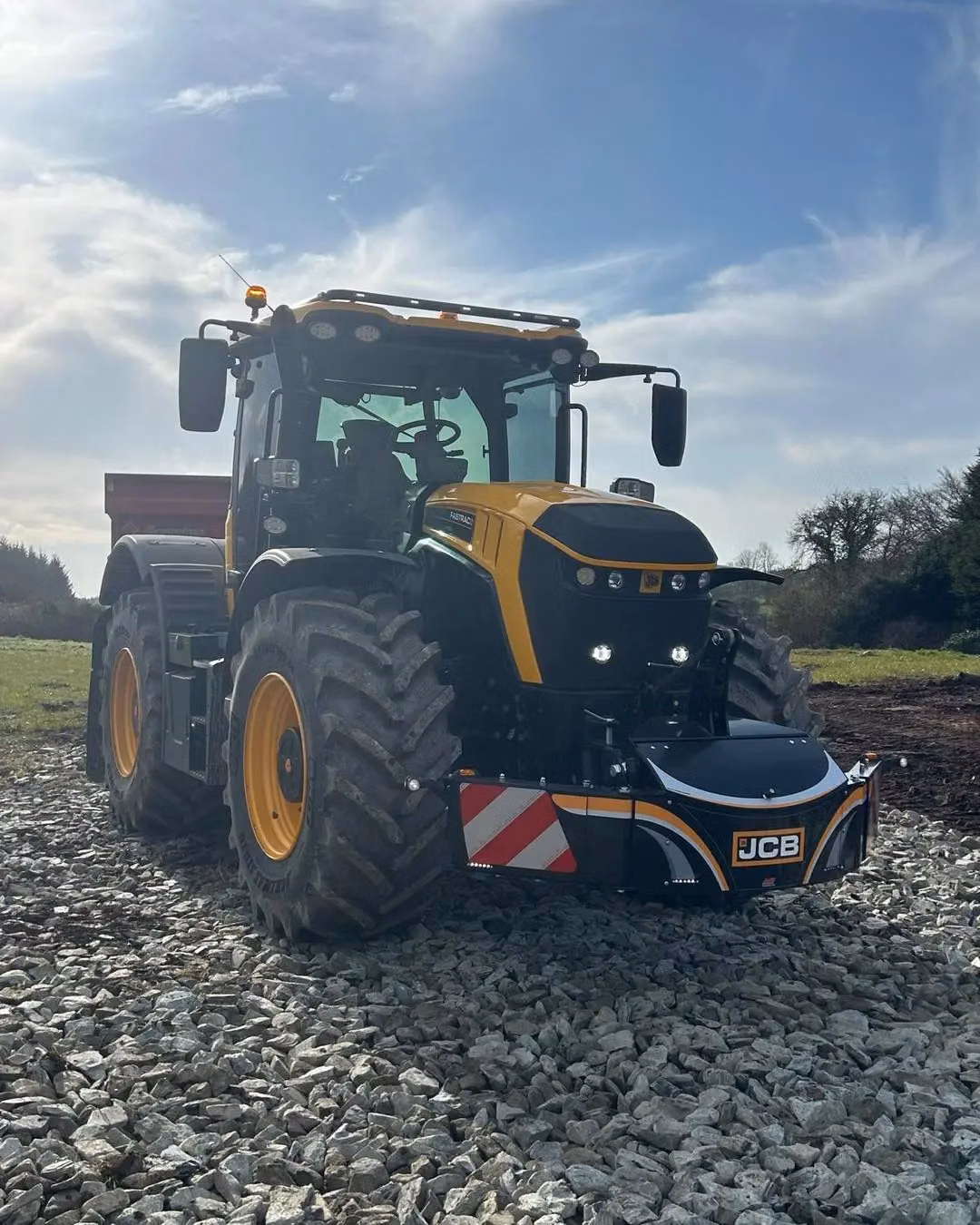 A tractor with large tires is fitted with a JCB branded front weight bumper featuring LED lights and hazard stripes