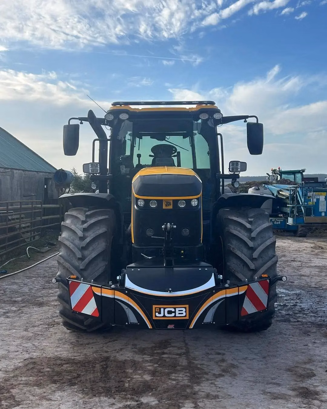 Black and yellow tractor with a front weight bumper displaying the JCB logo and red-white safety stripes