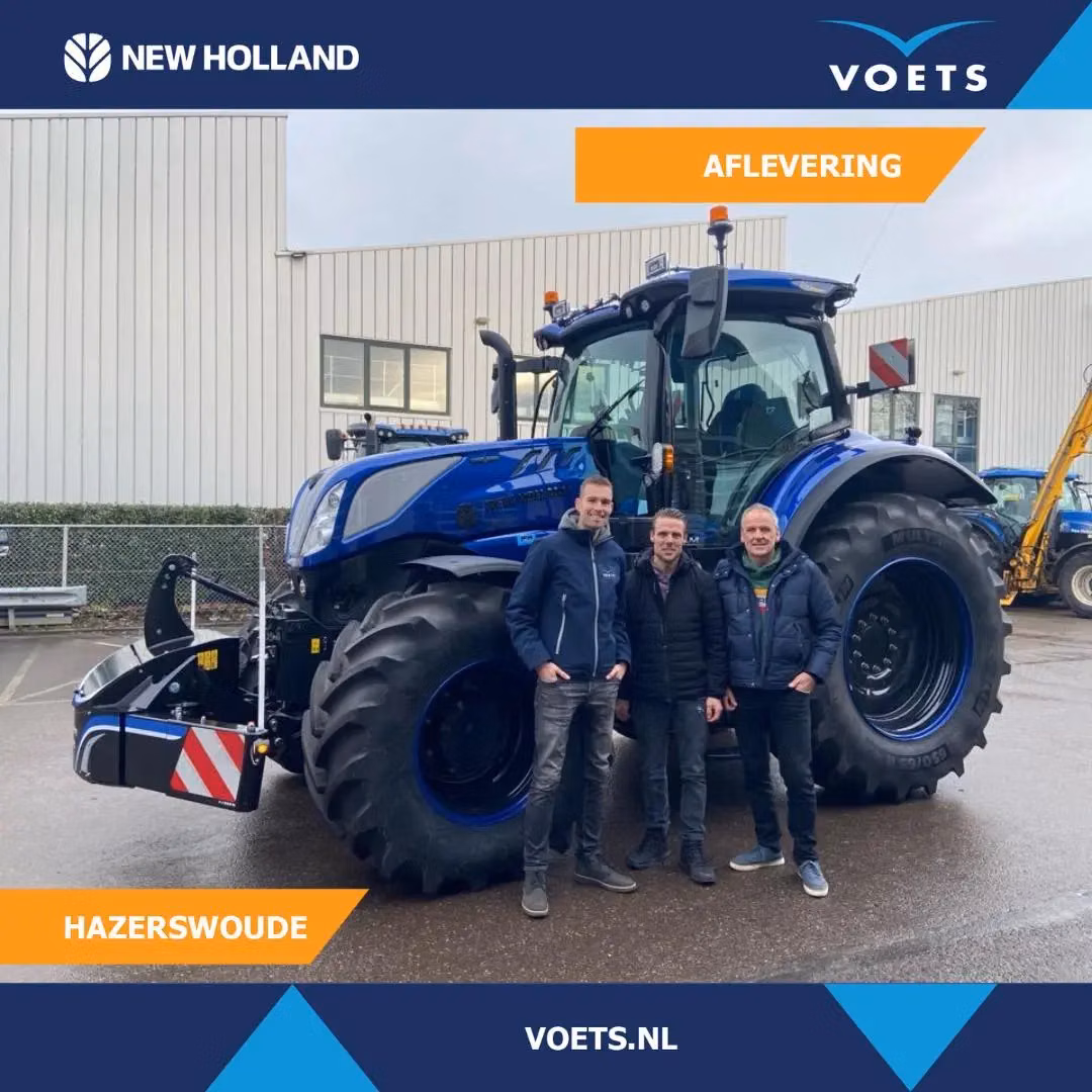 Three people stand in front of a large blue tractor fitted with a black front weight bumper in a paved industrial area