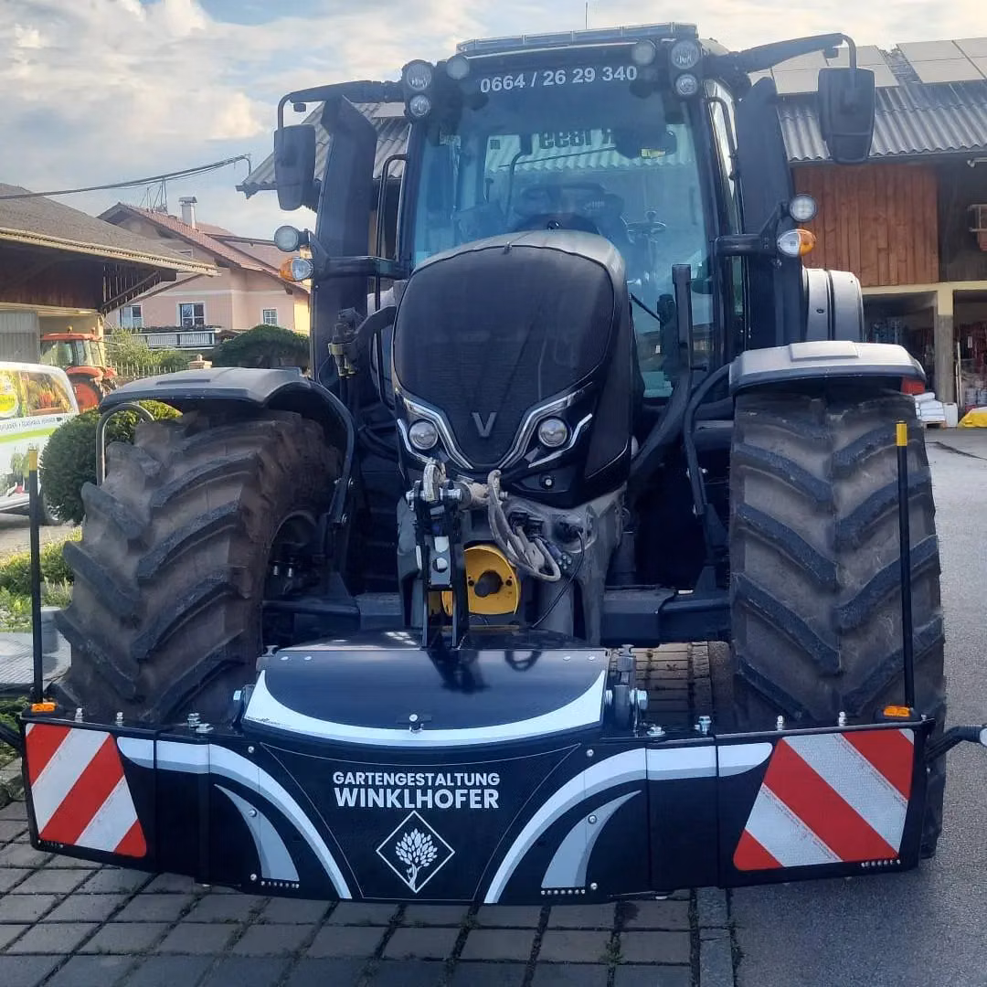 A large tractor with a mounted front weight bumper featuring reflective red and white panels and Winkelhofer branding