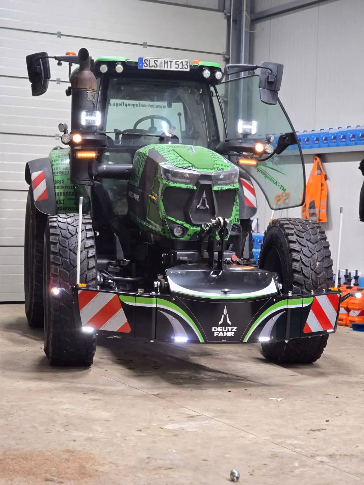 Tractor indoors with a mounted front weight bumper featuring LED lights and Deutz Fahr branding