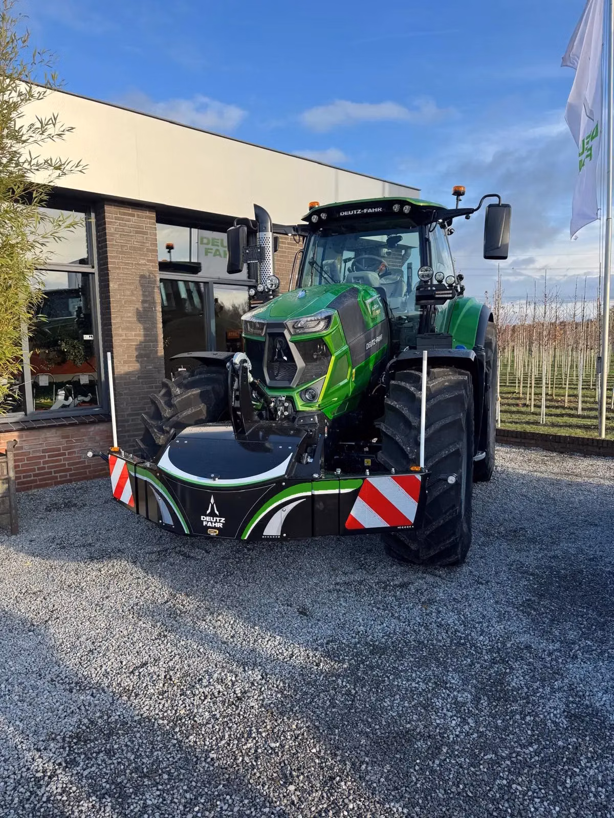 A green tractor with a large black front weight bumper featuring reflective stripes and Deutz-Fahr branding