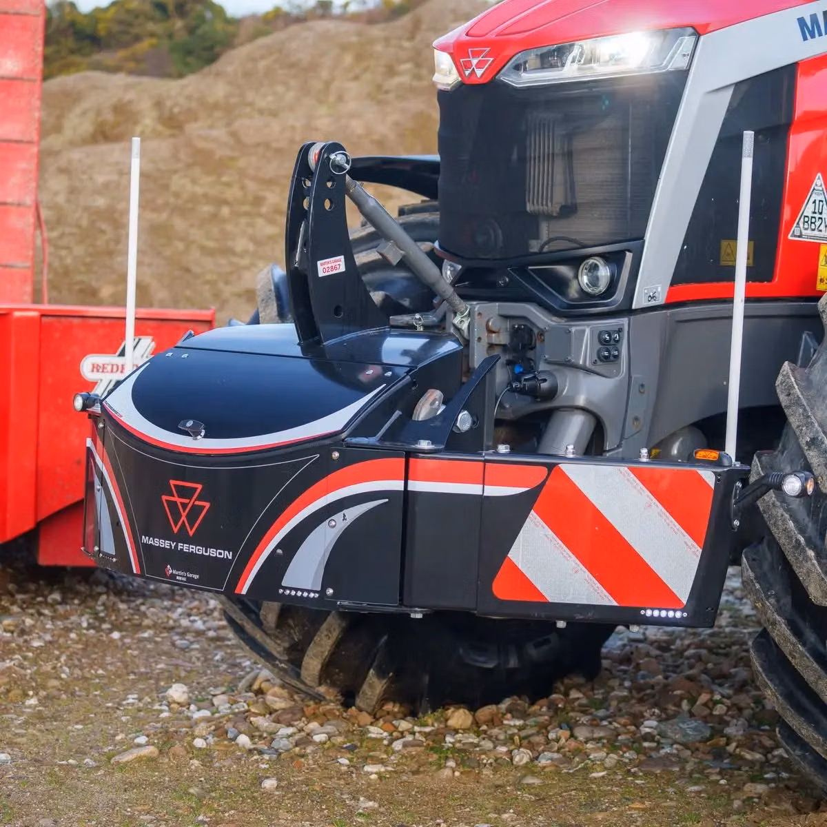 Front view of a Massey Ferguson tractor equipped with a black and red front bumper weight displaying safety stripes