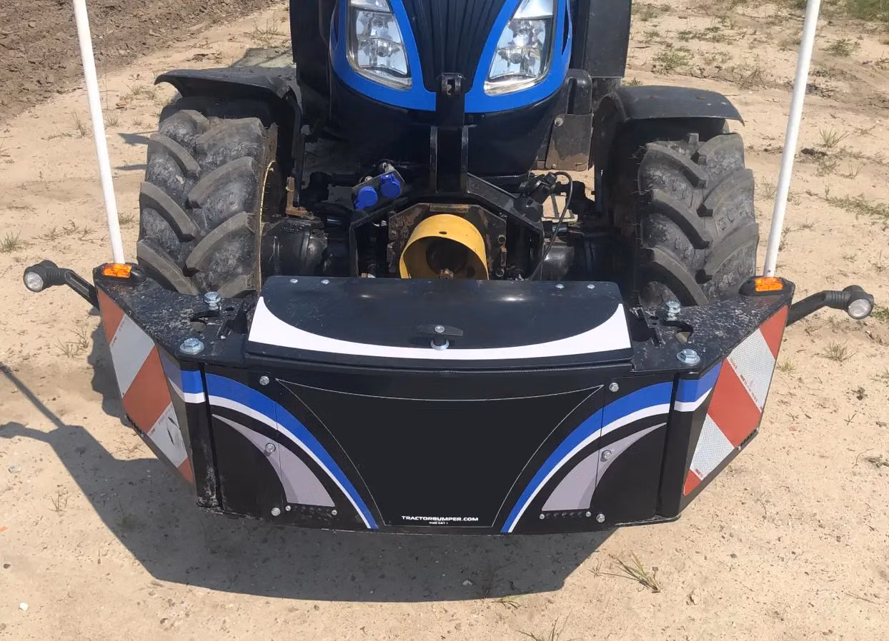 Front view of a tractor with a mounted front weight bumper featuring reflective panels and blue accents