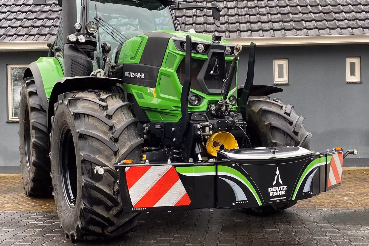 A green tractor fitted with a black Deutz-Fahr front weight bumper featuring reflectors and branding