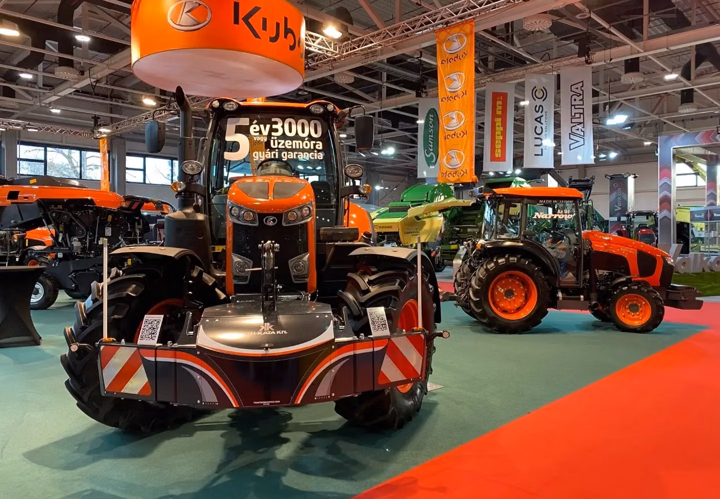 Orange tractor on display with a front weight bumper featuring reflective safety markings and a QR code.