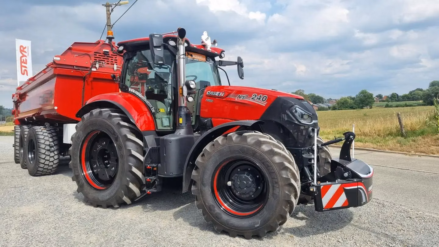 A red tractor with large tires is fitted with a front weight bumper featuring red and white safety stripes.