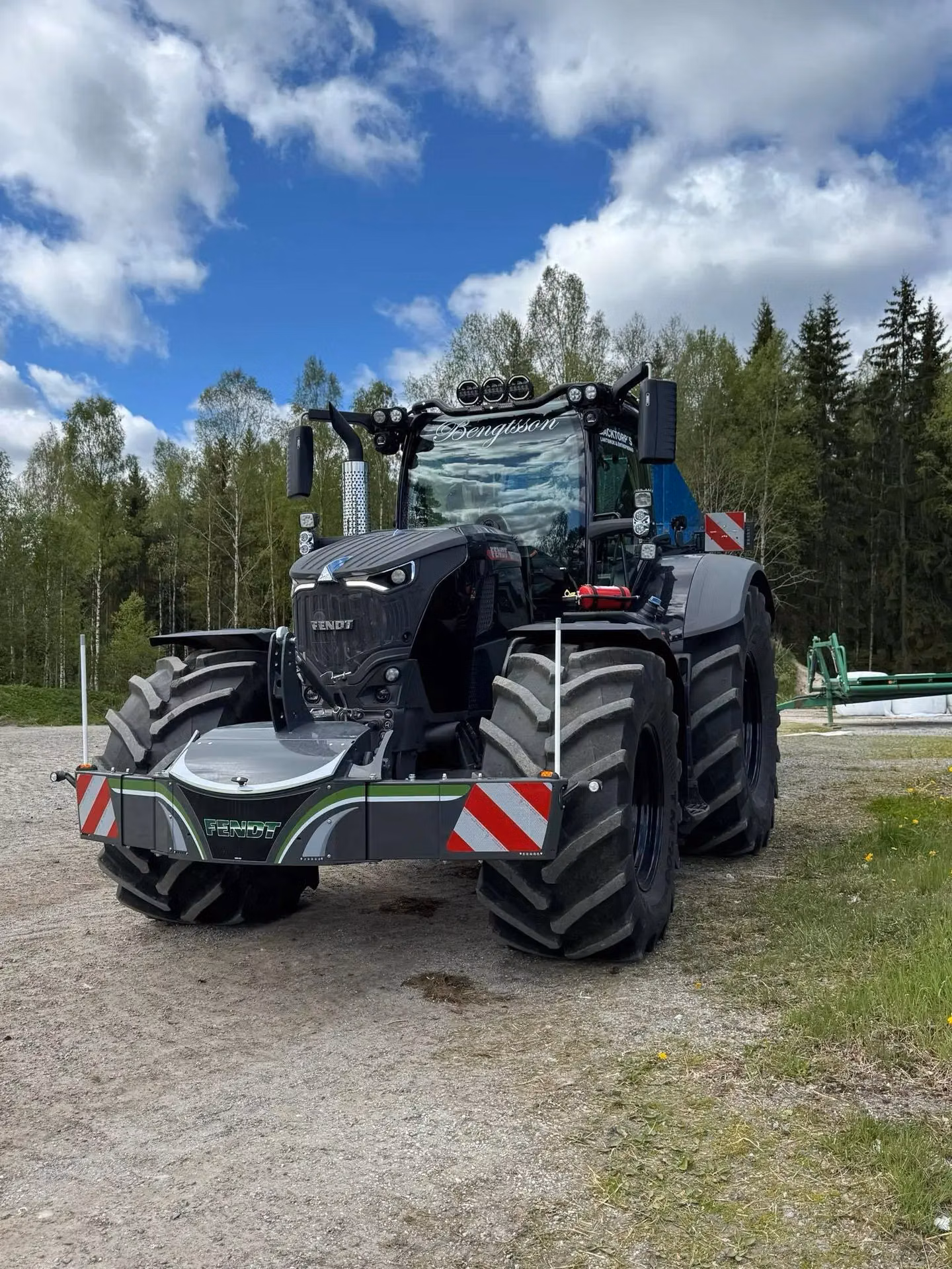 A large tractor fitted with a front weight bumper featuring LED lights and red and white reflective panels
