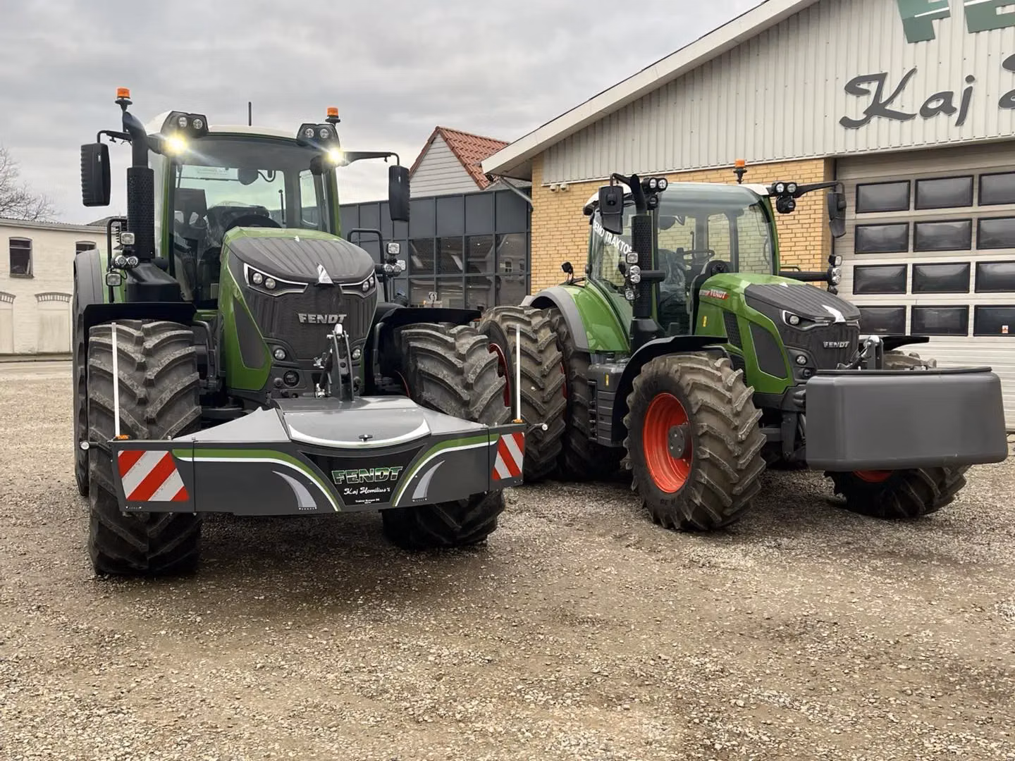 Two green tractors parked outside a building, each fitted with a different style of front weight bumper