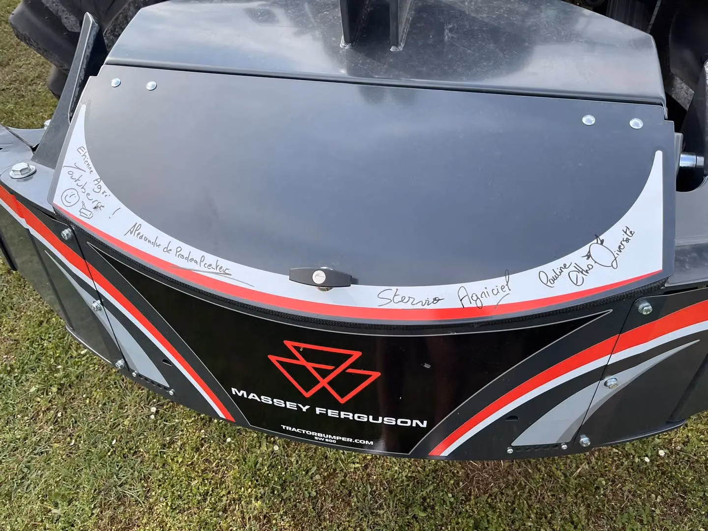Black and red Massey Ferguson front weight bumper with handwritten signatures and messages on the top panel