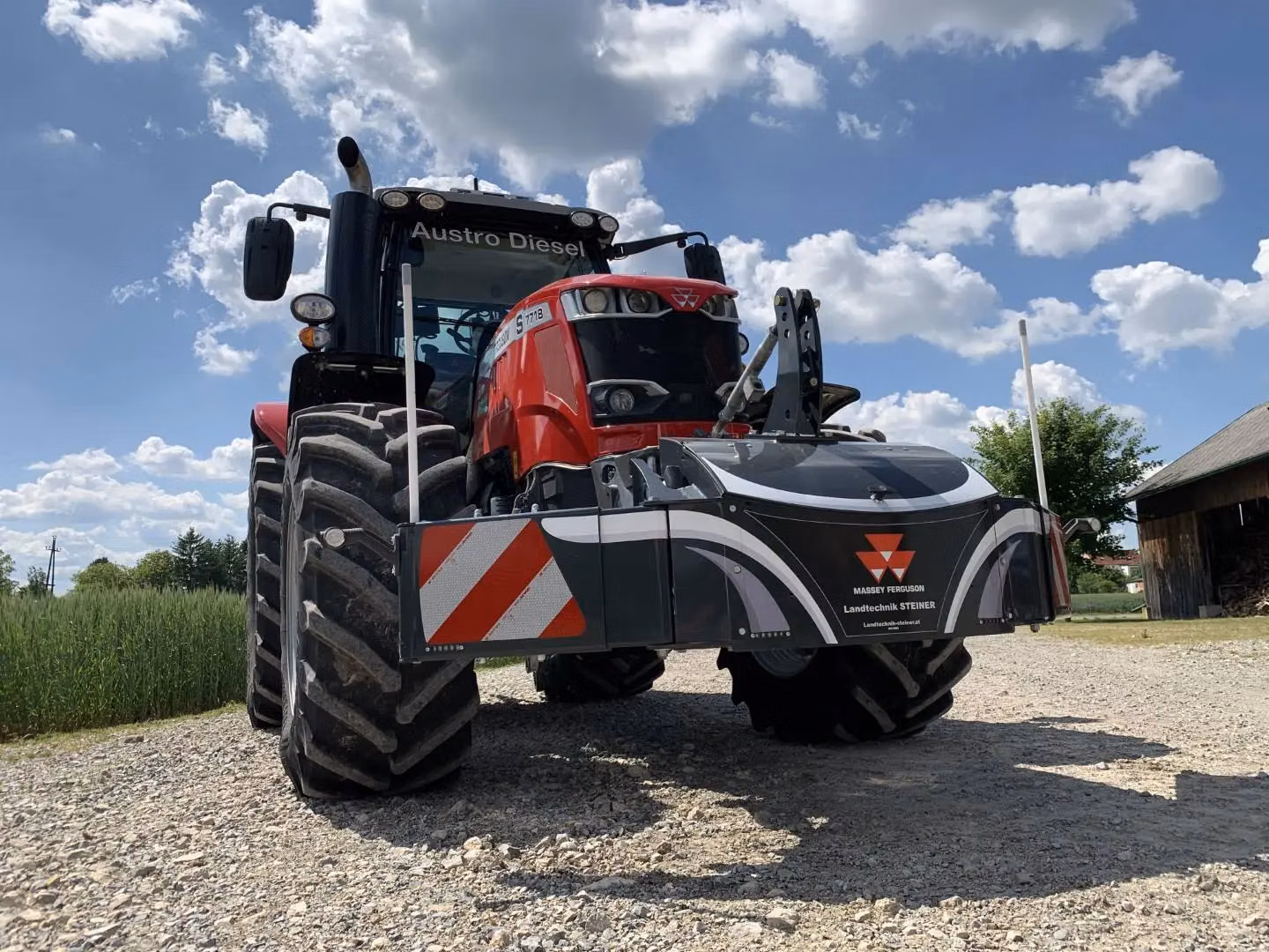 Red tractor with a Massey Ferguson branded front weight bumper featuring reflective stripes and LED lights
