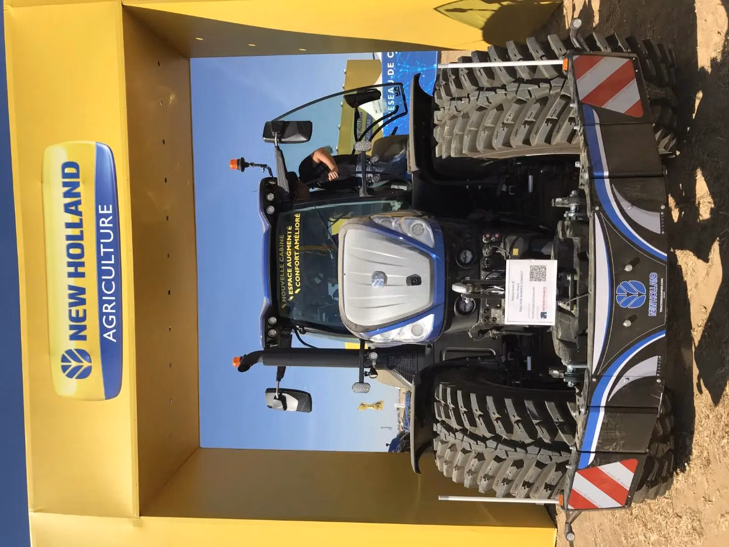 A tractor with large tires is fitted with a front weight bumper featuring reflective red and white stripes