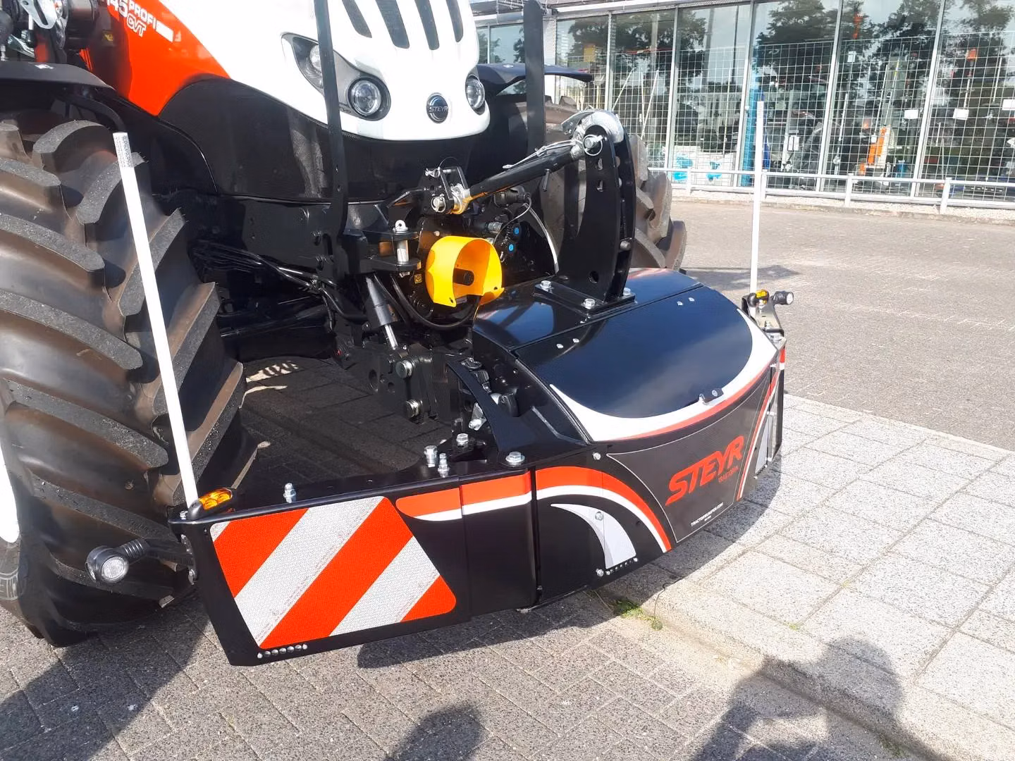 Front weight bumper with reflective red and white stripes and the STEYR logo mounted on a tractor.