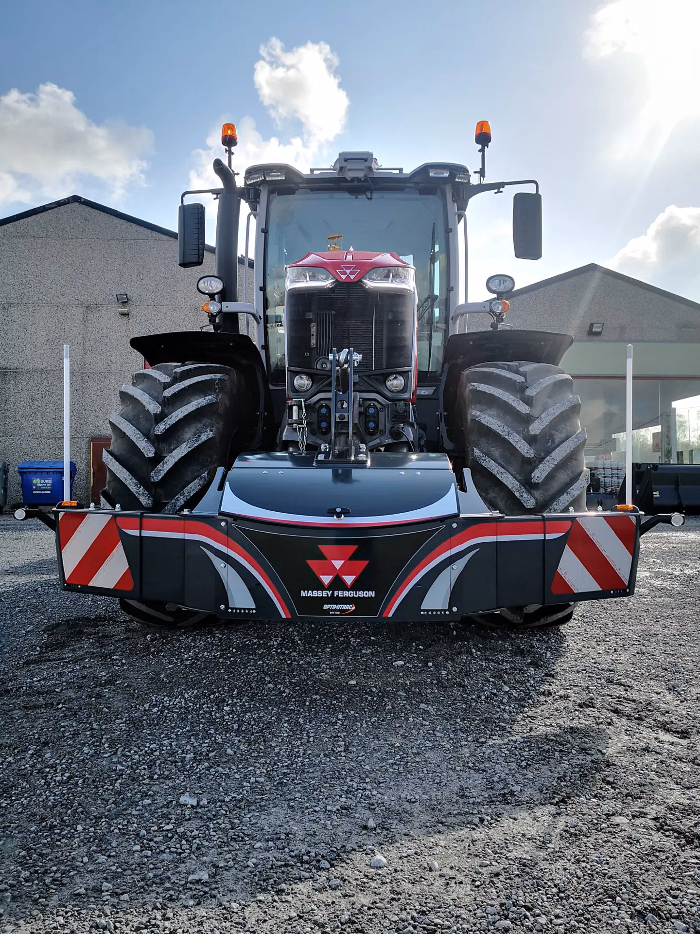 Front view of a Massey Ferguson tractor with a large front weight bumper displaying red and white reflective stripes