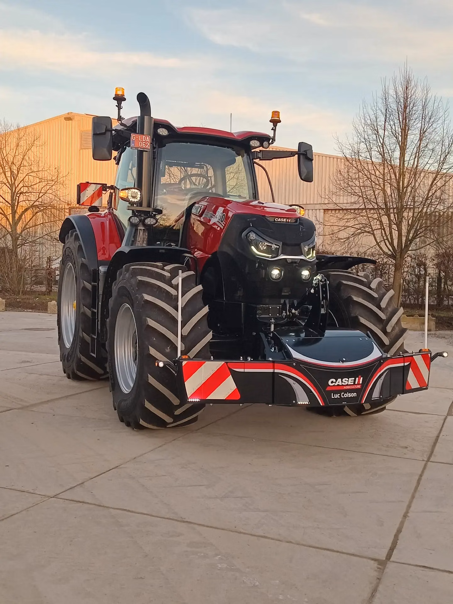 Red tractor with large tires and a CASE IH branded front weight bumper featuring red and white warning stripes