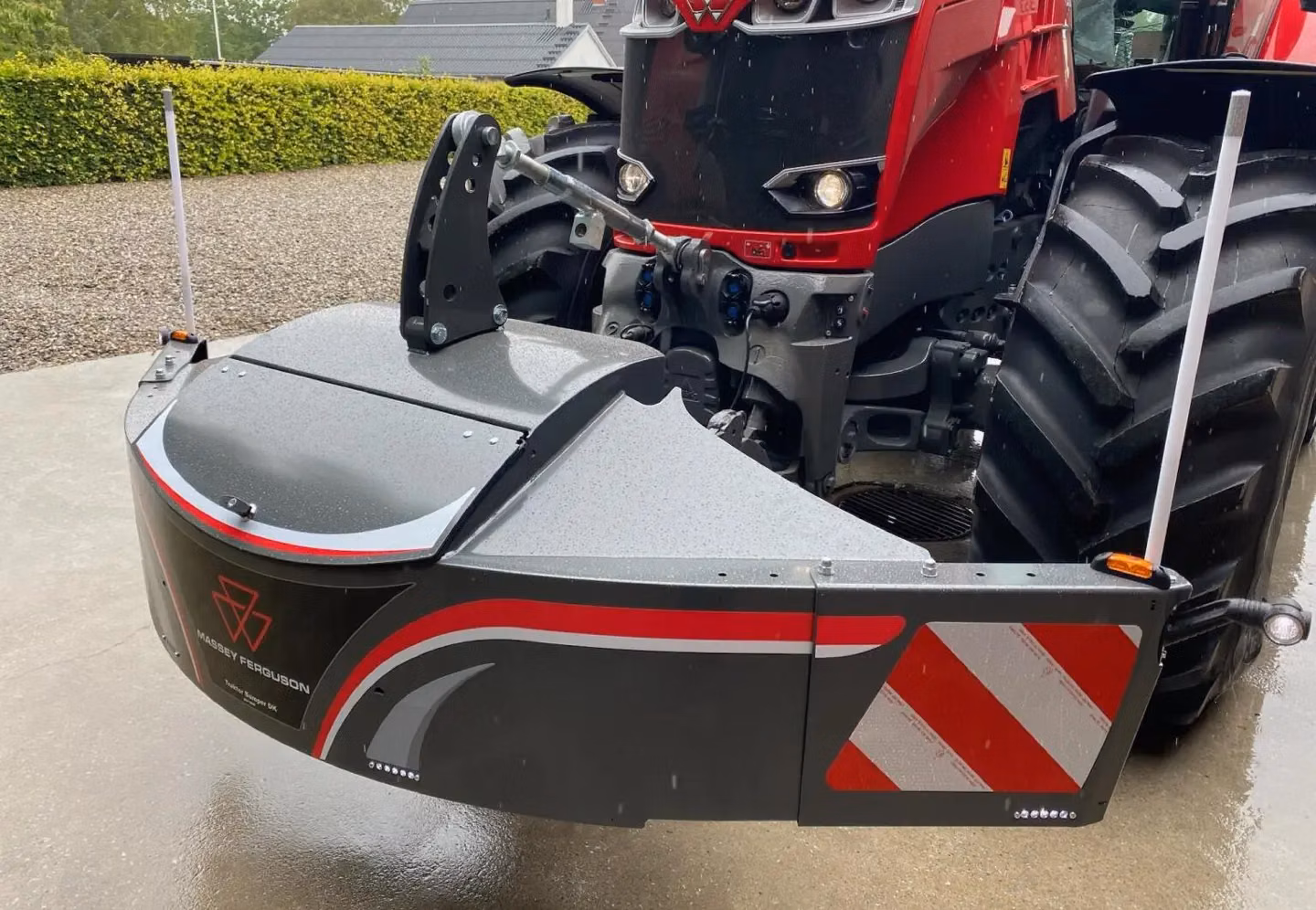 Large front weight bumper with red and white safety stripes and LED lights mounted on a red Massey Ferguson tractor