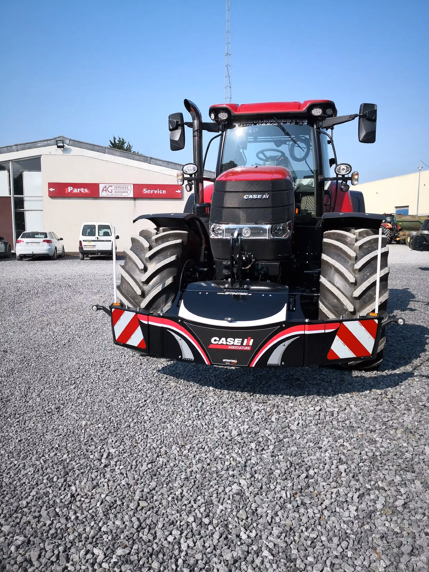 Red tractor with large front tires fitted with a CASE IH branded front weight bumper with reflective red and white panels