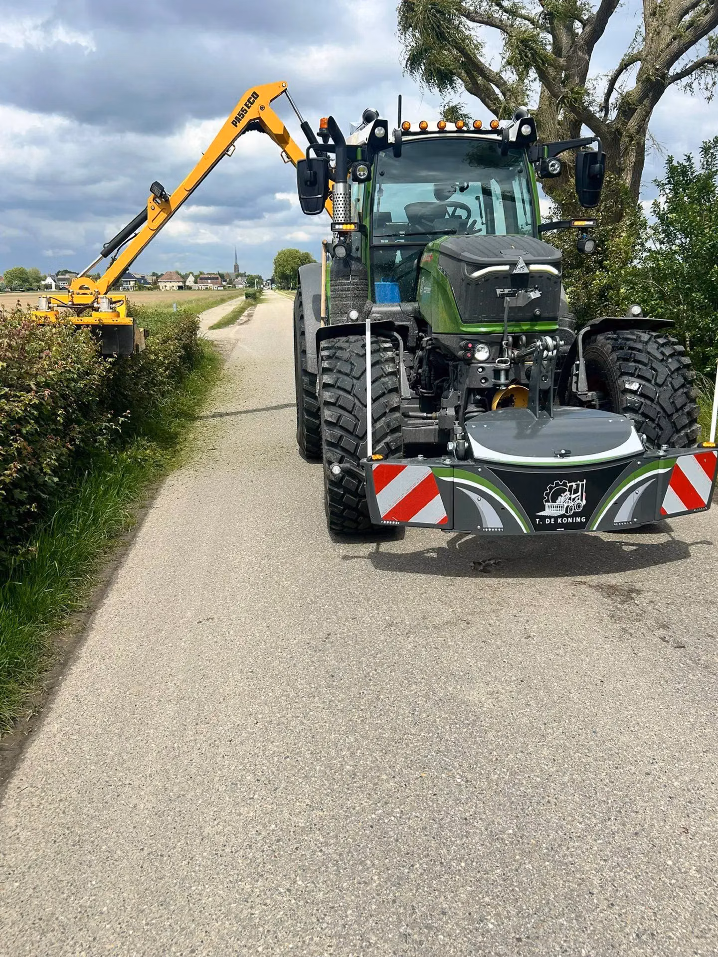 A tractor facing the camera with a front weight bumper and red-white safety stripes, parked on a rural road