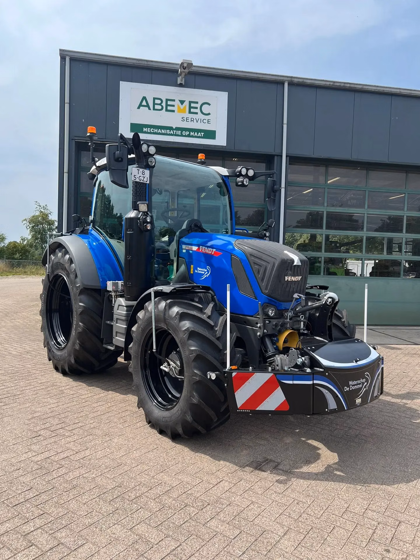 Blue tractor with a front weight bumper featuring red and white safety stripes and reflective markers