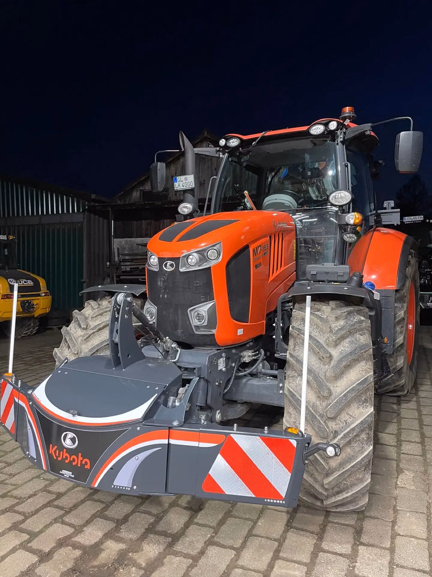 A tractor fitted with a Kubota-branded front weight bumper featuring red and white reflective panels
