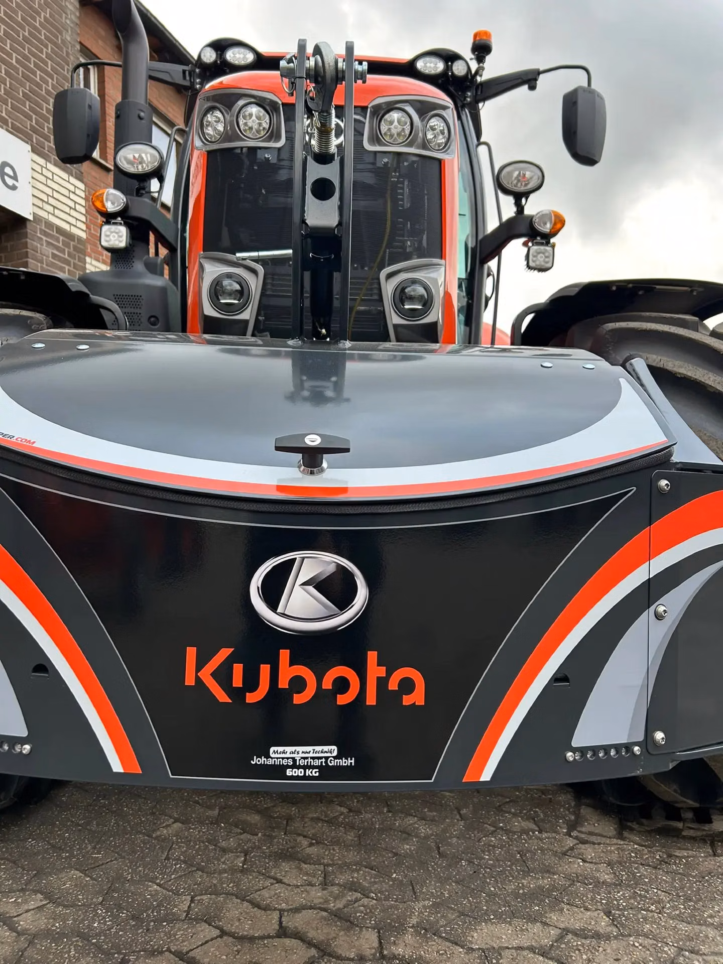 Front view of a tractor with a large black front weight bumper labeled Kubota and marked 600 kg.