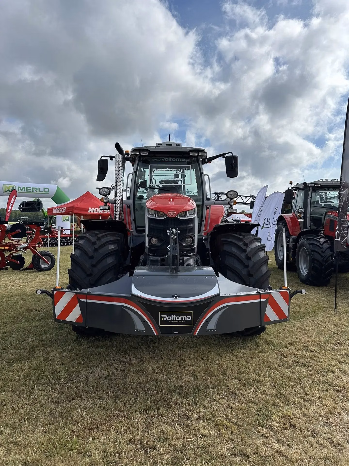 Red tractor with a large black front weight bumper featuring reflective stripes on display outdoors