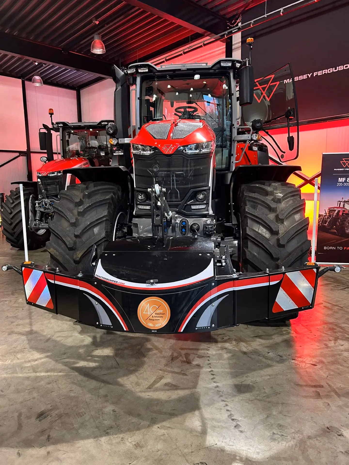 Red tractor indoors with a large black front bumper featuring reflective panels and a 40th anniversary badge