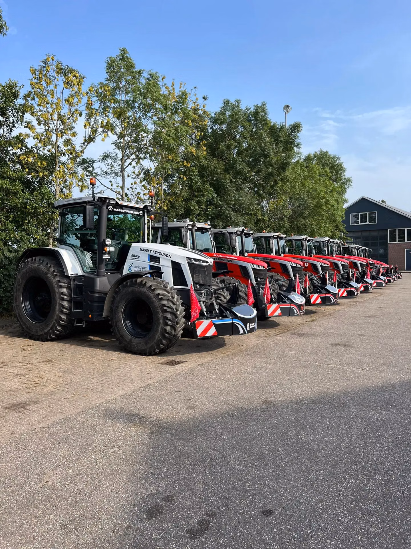 Row of tractors fitted with black front weight bumpers featuring red and white safety markings and LED lights