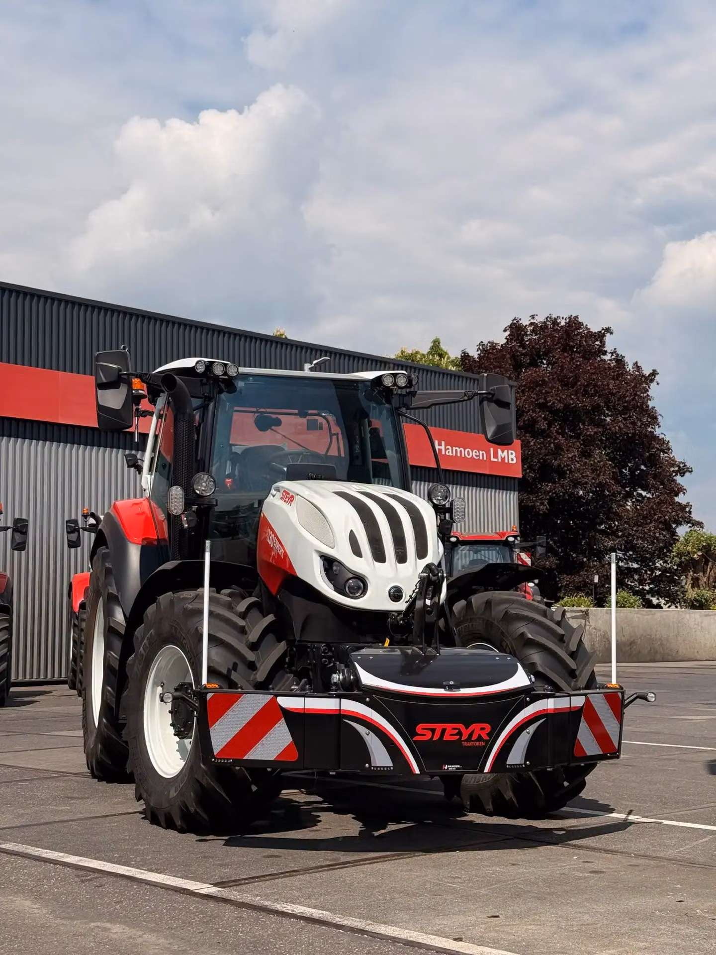A tractor fitted with a front weight bumper featuring LED lights, storage compartment and reflective red stripes