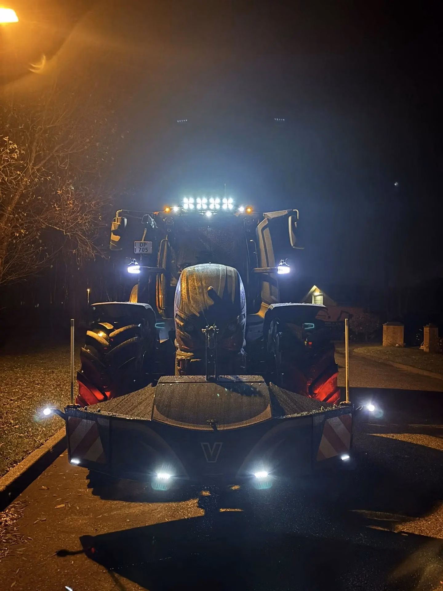 Tractor at night with illuminated front weight bumper featuring LED lights and reflective panels