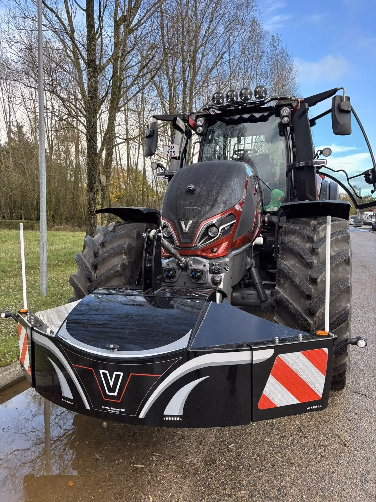 A tractor fitted with a large black front weight bumper featuring LED lights and red and white reflective panels