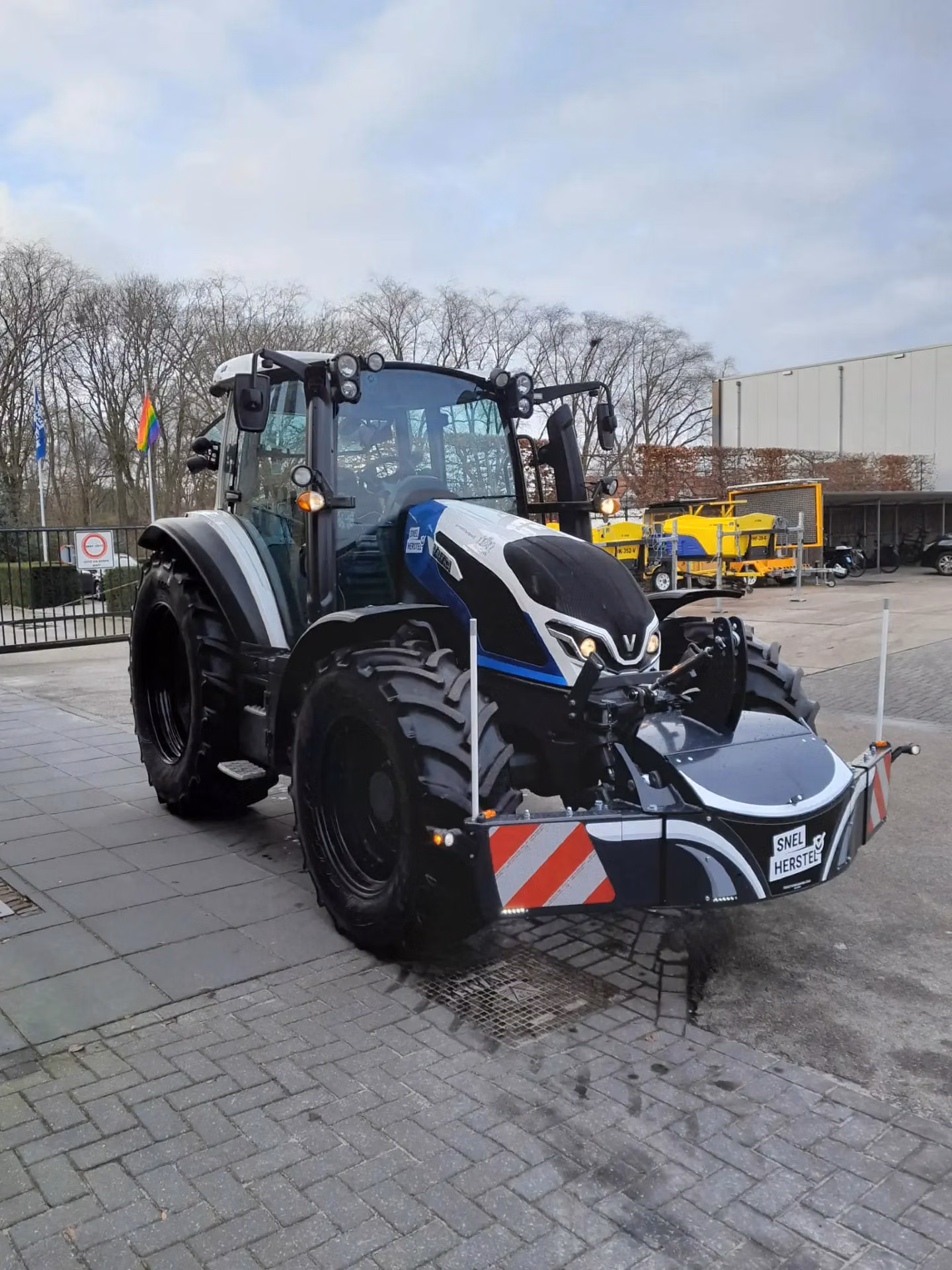 A black tractor fitted with a large front weight bumper featuring red and white reflective stripes
