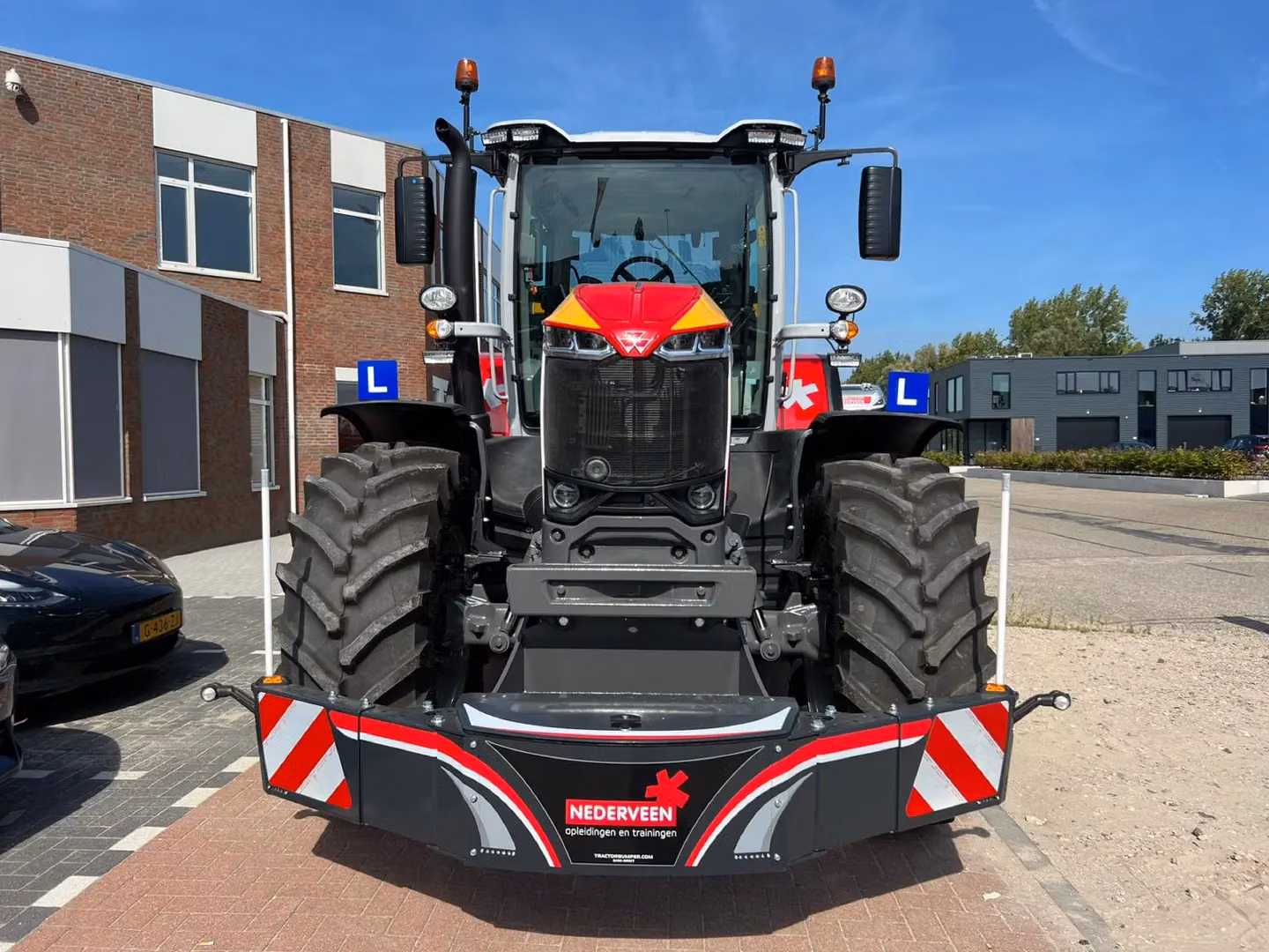 A front view of a tractor with a large, black and red front weight bumper featuring reflective stripes