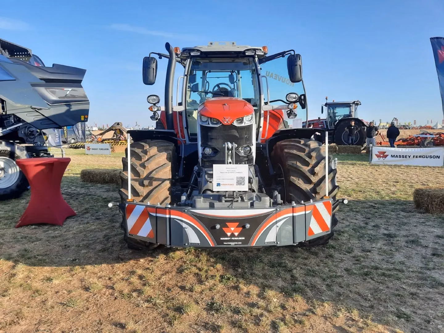 A Massey Ferguson tractor fitted with a front weight bumper featuring LED lights and safety markings on display outdoors