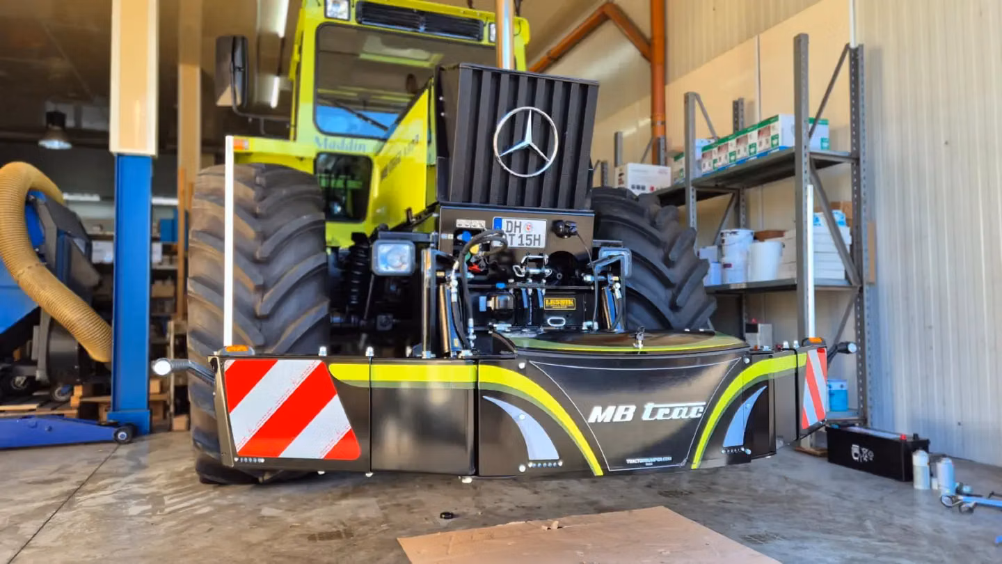 Front weight bumper with reflective red and white panels mounted on a tractor in a workshop with shelving in the background