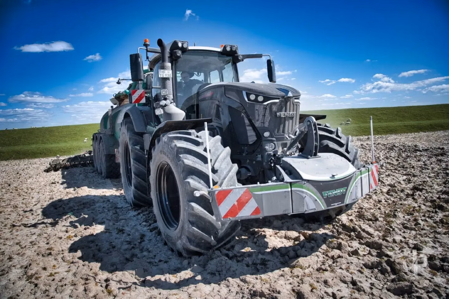 Large tractor with a front weight bumper featuring LED lights and red-white warning stripes on a plowed field