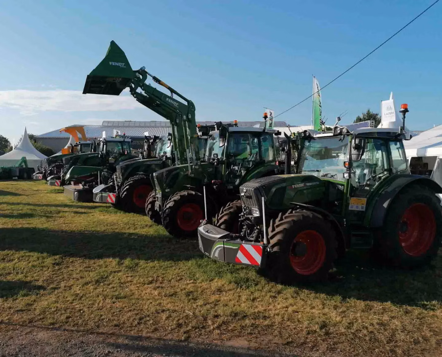 Several green tractors parked on grass, each equipped with large front weight bumpers featuring LED lighting panels