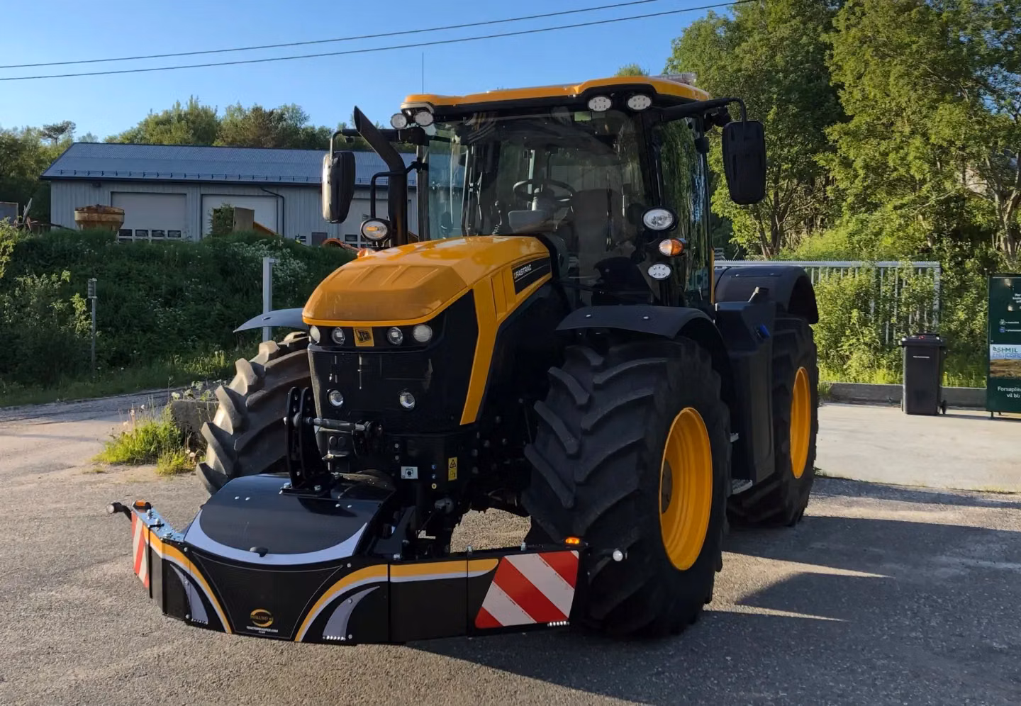 Yellow and black tractor with a large front weight bumper featuring reflective red and white panels