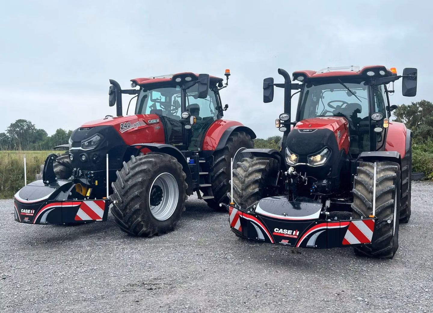 Two red tractors on gravel fitted with front weight bumpers featuring reflective stripes and Case IH branding