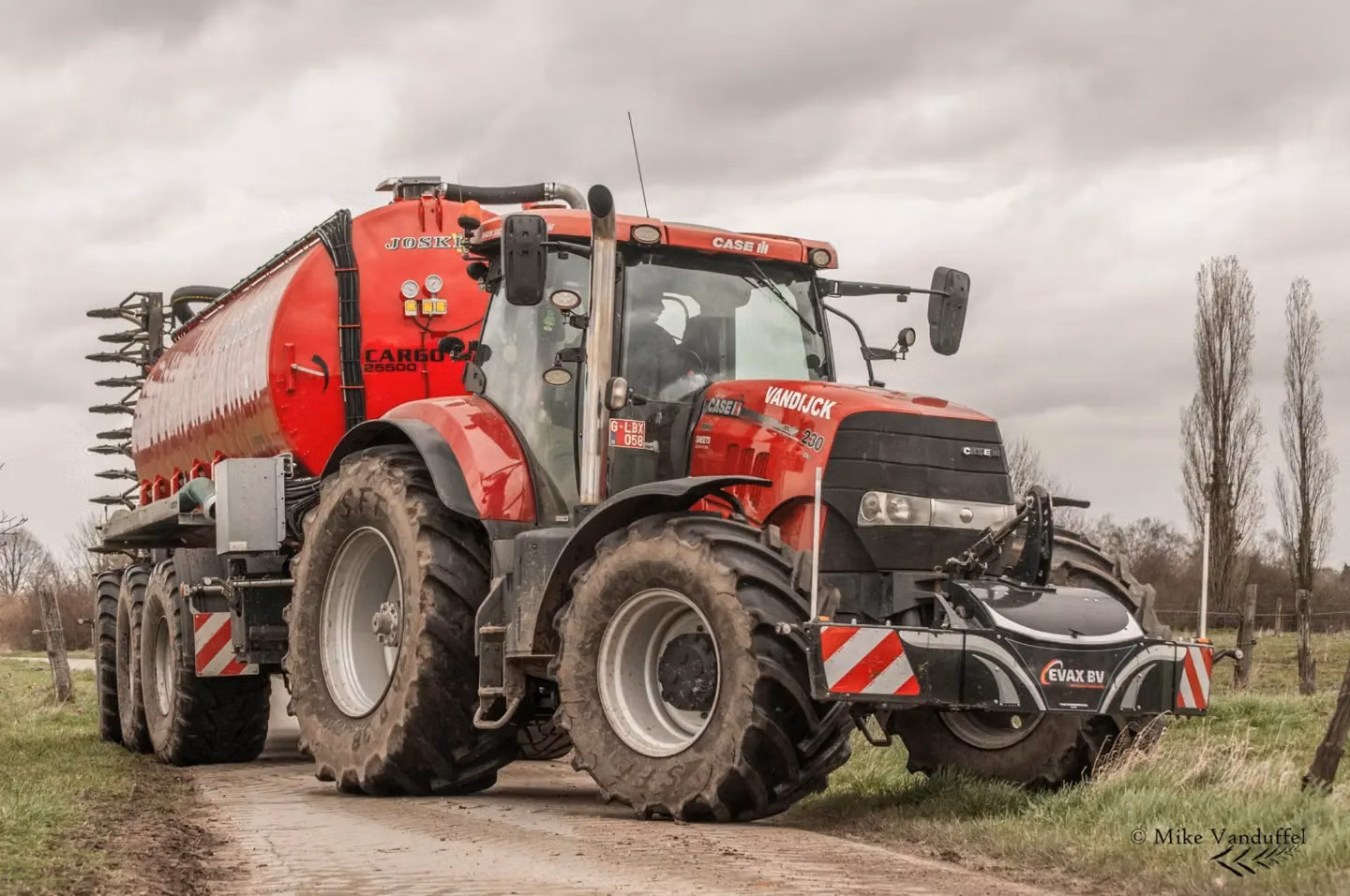 Red tractor with large tires on a dirt road, fitted with a black front weight bumper featuring red and white stripes