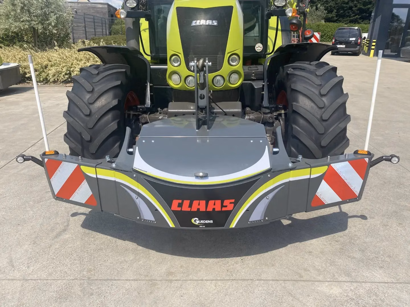 Front view of a tractor with a gray front weight bumper featuring red and white reflective panels and CLAAS branding
