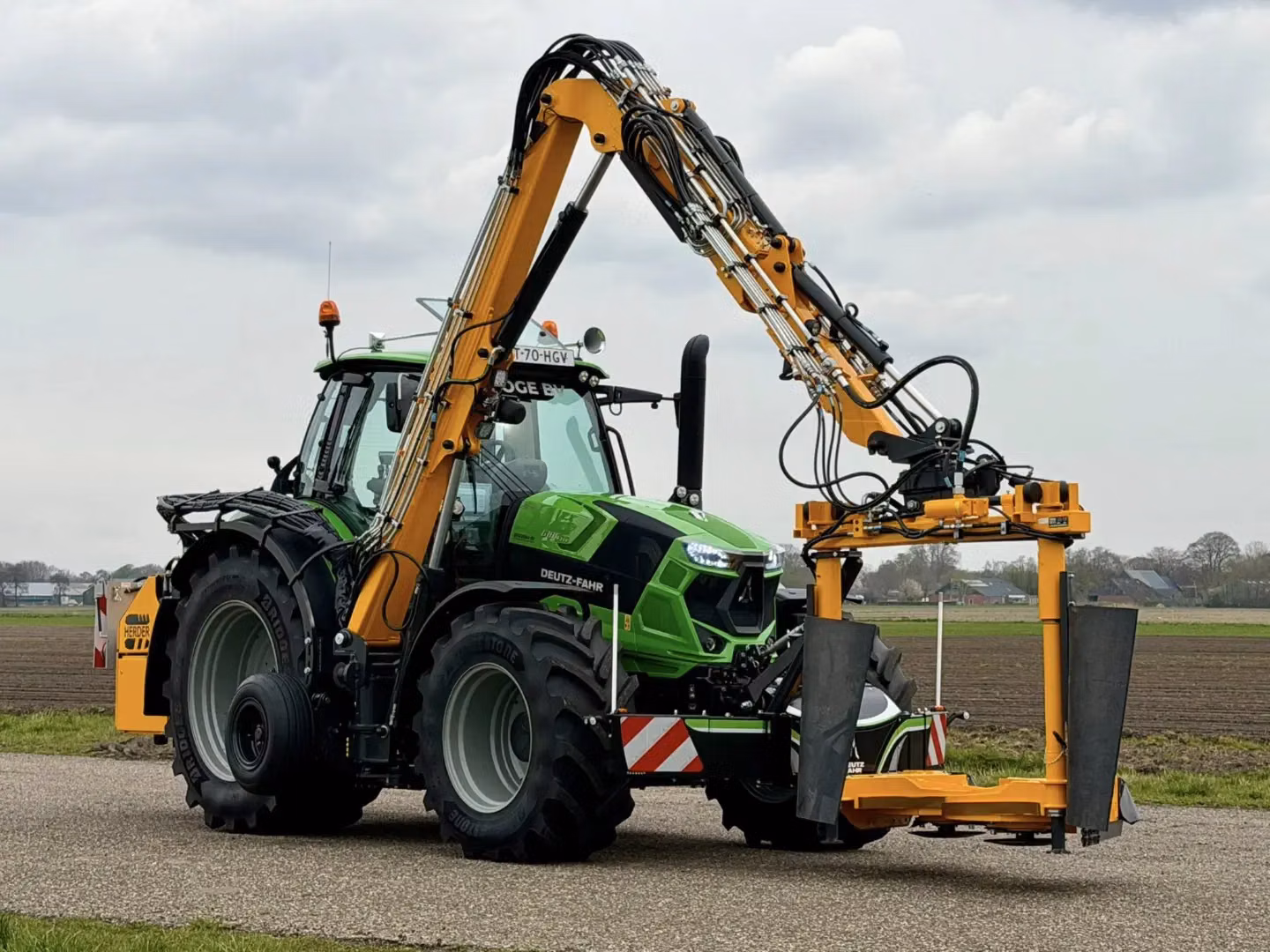Green tractor with large tires and a mounted yellow front weight bumper attachment on a rural road