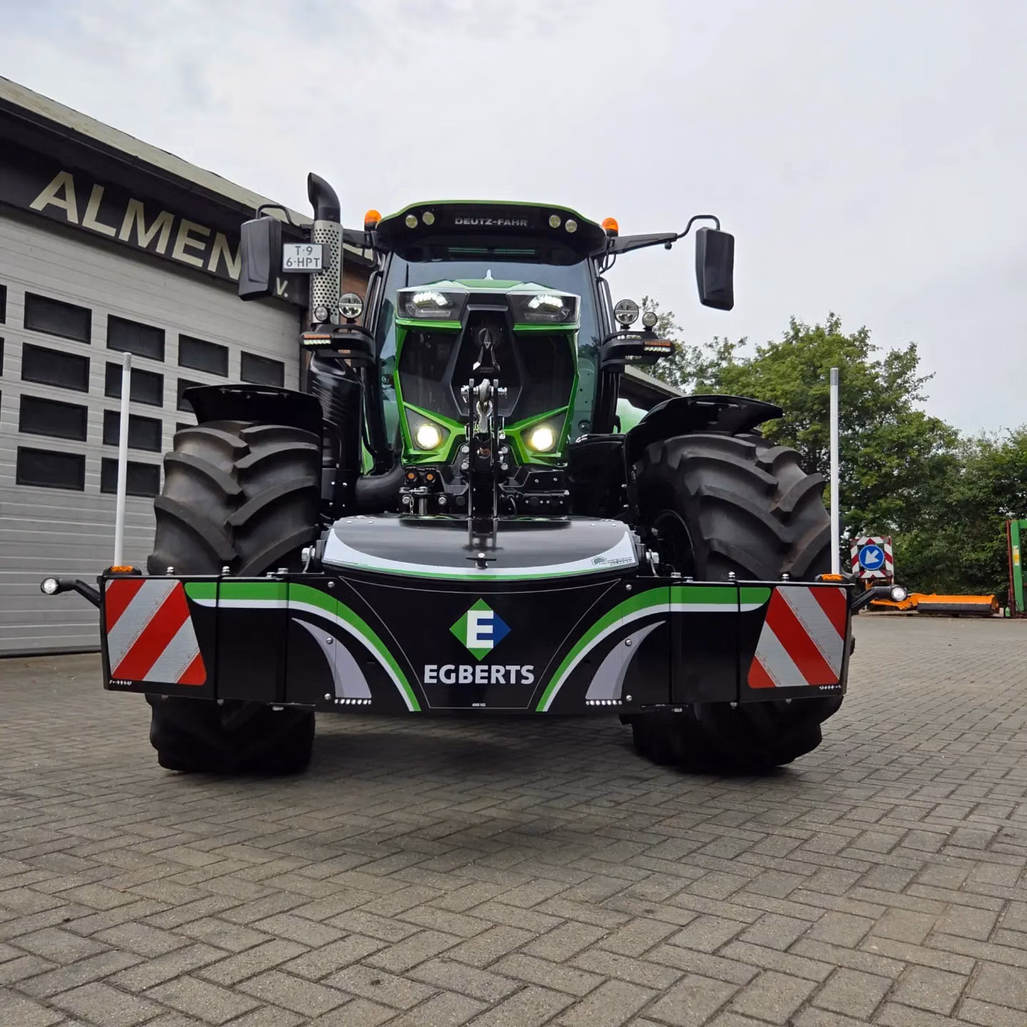 Green tractor with large front weight bumper featuring LED lights and Egberts branding, parked on pavement