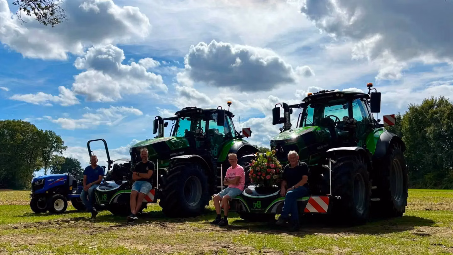 Three people sit on green front weight bumpers attached to two large tractors with a smaller blue tractor nearby