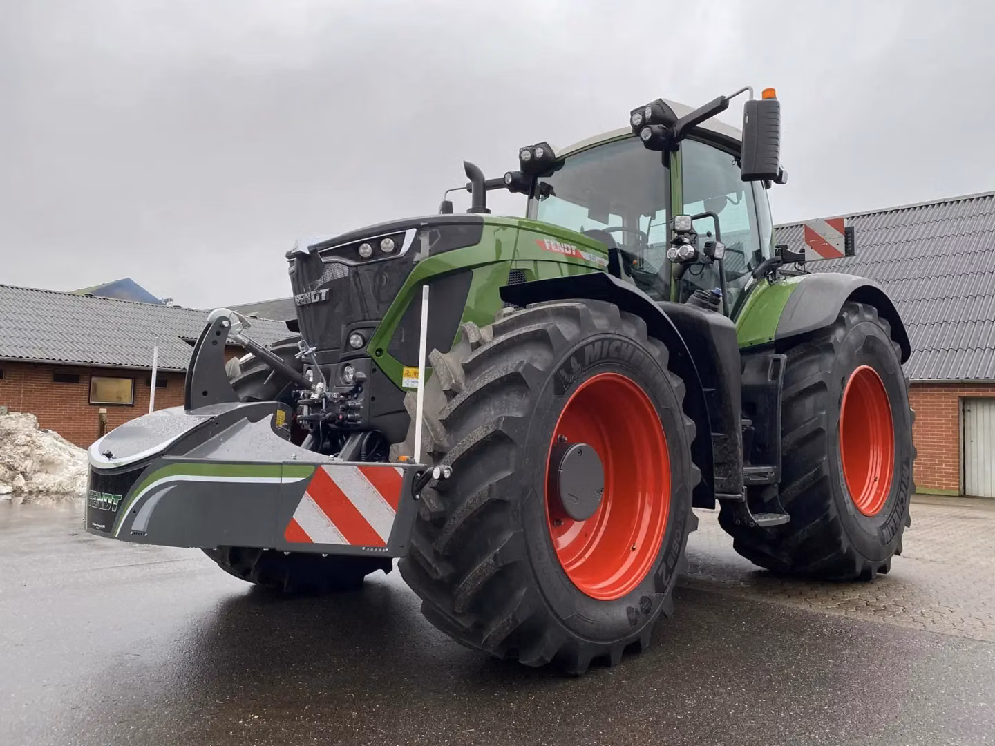 Large green tractor with red wheels is fitted with a front weight bumper featuring reflective red and white stripes