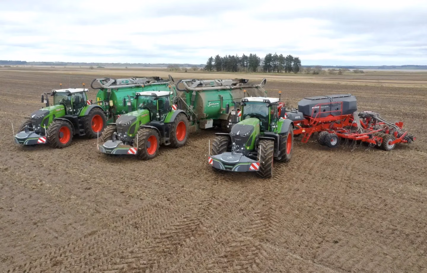 Three green tractors in a field, each fitted with a front weight bumper with lights and red-white safety markings